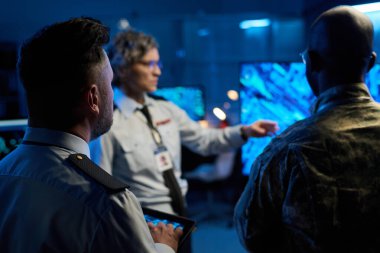 Etkileşimli ekranda sunum yapan iki kültürler arası erkek memurun kadın meslektaşlarının önünde dikey görünümü