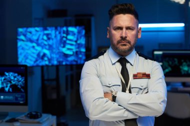 Askeri Komuta Merkezi 'nin ciddi olgun erkek subayı. Kollarını kavuşturup kameraya bakıyor.