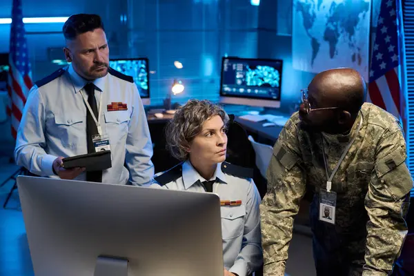 Masaüstü bilgisayarı önünde tartışırken Afrika kökenli Amerikalı genç bir erkek subaya bakan ciddi olgun bir kadın.