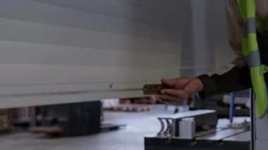 Orta boy iki Asya ve Afrika kökenli Amerikalı erkek işçinin güvenlik üniforması içinde paten kapısından geçip gündüz vardiyası için endüstriyel depoya girerken görüntüsü.