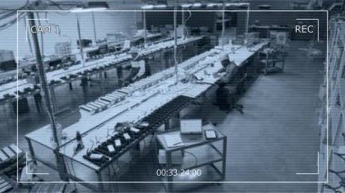 Yüksek açılı CCTV güvenlik kamerası görüntüleri atölyede çalışan iki farklı ışık fabrikası uzmanı, endüstriyel lambaları birleştiriyor, teknik çizimleri ve dizüstü bilgisayardaki özellikleri kontrol ediyor.