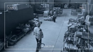 Geniş açılı CCTV güvenlik kamerası görüntüleri. Geniş bir depoda çalışan erkek çalışanlar ve görünürlük yelekleri. Hidrolik tramvayda kutular taşıyarak paletleri kontrol ediyorlar.