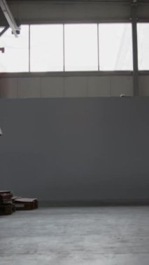 Üniformalı erkek depo görevlisinin tam dikey kilit görüntüsü, sarı görünürlük ceketi, karton bir kutu dolusu eşya taşırken, tatmin merkezinde çalışırken.