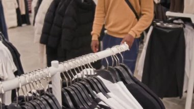 Sıradan giysiler içinde, uzun kollu mağazayı seçen kimliği belirsiz bir adamın orta bölüm fotoğrafı.