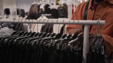 Tanımlanamayan bir erkek müşterinin siyah kot pantolon raflarına bakarken doğru boyutu seçerken Slowing mağazasından alışveriş yaparken görüntüsü.