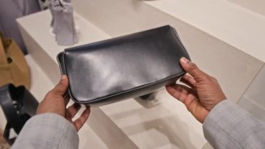 Siyah deri çanta tutan, el ele verip dükkandaki aksesuarları seçen tanınmamış bir kadının POV fotoğrafı.