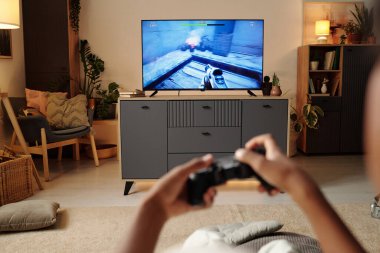 Samimi oturma odasında TV 'de oyun oynarken oyun kumandası. Mobilyalar konfor ve rahatlama için ayarlanmış, sıcak, davetkar bir ortam yaratıyor.