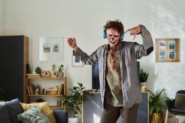 Kanlı giysiler içindeki erkek zombi, kablosuz kulaklık takıyor, müzikten hoşlanıyor, oturma odasında dans ediyor, fotokopi çekiyor.