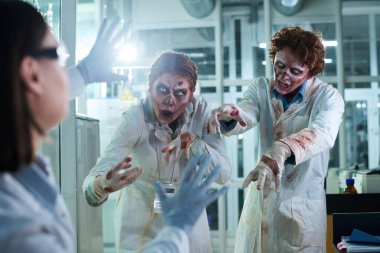 Zombi kostümü giyen iki genç kadın meslektaşı korkutuyor, gece geç saatlere kadar laboratuarda çalışıyorlar.