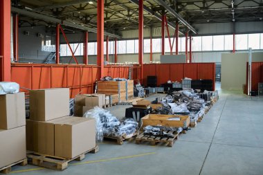 Bir sıra ahşap paletler, paketlenmiş karton kutular ve modern fabrikada üretilen yedek parçalar.