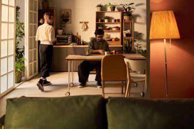 Modern dekor ve bereketli bitkilerle çevrili ev işleriyle meşgul olan çift rahat ve verimli bir ortam yaratıyor.