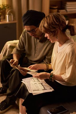 Beyaz çift ev ofis ortamındaki mimari planları inceliyor, tartışma ve işbirliği içinde, planlama ve tasarım konularına odaklanıyor