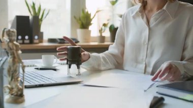 Beyaz bluzlu kadın avukat yardımcısı ya da hukuk asistanı resmi mühürlü belgeleri imzalarken aynı zamanda hukuk firmasında ya da noterlik bürosunda evrakları yönetirken orta ölçekli bir orta bölüm fotoğrafı.