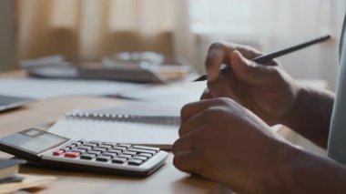 Tanımlanamayan siyahi adamın elleri hesap makinesine yaşam masraflarını ve kamu giderlerini topluyor, sonra da aile bütçesini yönetirken deftere topladığı tutarı yazıyor.