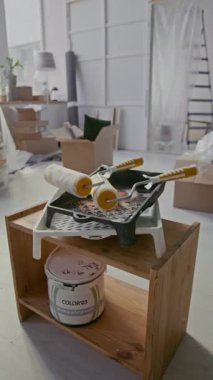 Yenileme çalışmaları sırasında yeni apartmanın oturma odasındaki tahta mobilyaların üzerinde duran plastik tepsilerin dikey görüntüsü.