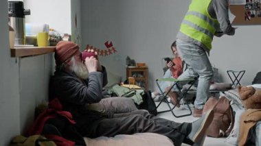 Tam tebessüm eden beyaz erkek gönüllü ya da sarı yelekli sosyal görevli mülteci kampında yatağında çay içen, sorgulayan ve tablet üzerindeki kontrol listesini dolduran son sınıf öğrencisine yaklaşıyor.