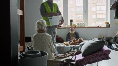 Sarı yelekli gönüllülerin mülteci sığınağında dolanıp savaş, felaket, sel ya da kasırga nedeniyle yerlerinden edilen insanlara şişe su ve battaniye dağıttığı geniş kapsamlı bir çekim.