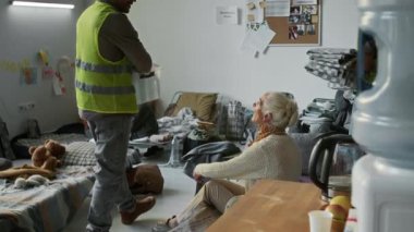 Sarı yelekli gönüllülerin, doğal afetten etkilenen anne, çocuk, yaşlı erkek ve yaşlı kadınlara içki şişeleri ve battaniyeler dağıtarak mülteci sığınağında kalmalarını sağlayan tam bir çekim.