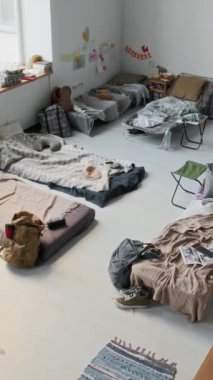Mülteci sığınağındaki yatakların, katlanabilir yatakların, sandalyelerin, kişisel eşyaların, battaniyelerin olduğu komple yüksek açılı CCTV güvenlik kamerası görüntüleri.