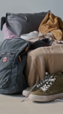 Sırt çantası, yerde haki rengi spor ayakkabılar, yatağın yanında ya da yastıklı battaniyeli yatak, evsiz insanlar için sığınak, pansiyon ya da yatakhane yok.
