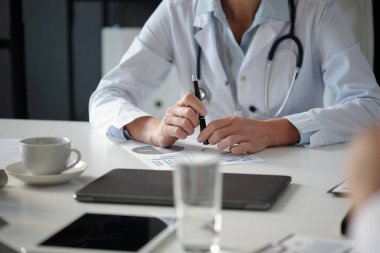 İş yerindeki tanınmayan kadın doktorların veri raporlarını ve istatistiksel çizelgelerini elinde kalem kopya alanı tutarak incelerken görüntülerini kapat.