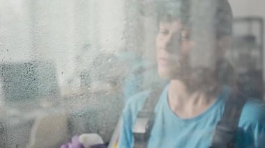 Kafkas kadın çalışanın modern ofiste cam yüzeyi deterjanla yıkarken orta boy fotoğrafı.
