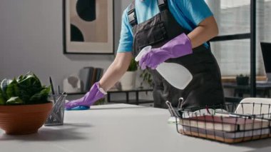 Ofiste masaları silerken beyaz bir kadının deterjan sıkarken elde çekilmiş fotoğrafı.