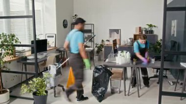 İki çok ırklı temizlikçinin iş kıyafetlerini yıkadıkları ofis alanlarını profesyonel ekipmanlarla uzun zaman önce çekmişler.