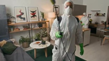 Koruyucu giysili erkek dezenfektanının cam yüzeyini spreylemesi ve kadın meslektaşıyla iç mekanda çalışması zor bir ihtimal.