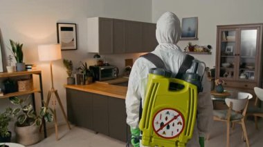 Tehlikeli madde giysisi giymiş, böcek ilacı spreyini kullanan ve düz kameraya bakan genç erkek işçilerin el yapımı portresi.