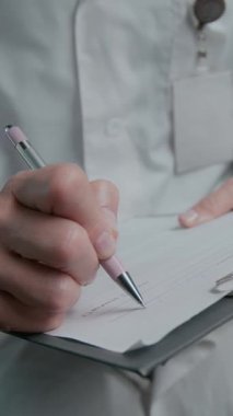 Beyaz önlüklü, tanınmayan kadın radyografın beyin MR raporu yazan ve bilgisayar ekranındaki taramaları incelerken yorumladığı dikey görüntü.