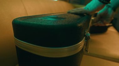 Hardcase 'i açan ve loş neon ışıklı odada gitar çalan isimsiz müzisyenlerin yakın plan fotoğrafları.