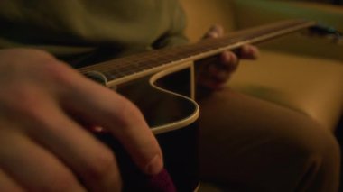 Tanınmayan müzisyenin, akustik gitar vücudunu yumuşak havluyla silerken, içerideki telli çalgılarla ilgilenirken yakın plan çekimleri.