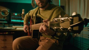 Sakallı ve uzun saçlı beyaz gitaristin gitar tıngırdatırken, modern neon ışıklı kayıt stüdyosunda telli enstrüman çalarken, podcast ya da performansa hazırlanırken.