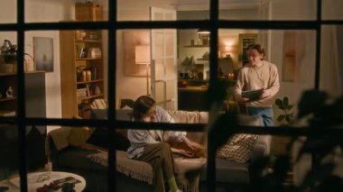 Geniş açı, pencereden bakıldığında dizüstü bilgisayarı olan beyaz bir adamın oturma odasına koşması, yeni bir iş bulduğuna dair mutlu haberleri paylaşması, hem tezahürat yapması hem de kucaklaşması.