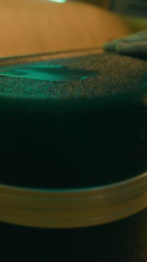 Hardcase 'i açan ve loş neon ışıklı odada gitar çalan isimsiz müzisyenin dikey yakın çekimi.