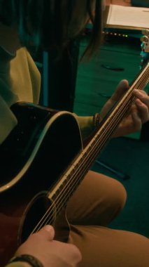 Erkek gitaristin akustik gitarda yeni şarkılar tıngırdattığı, melodiyi öğrendiği ve modern neon ışıklı stüdyoda kayıt yapmaya hazırlandığı dikey kesim sahneleri.