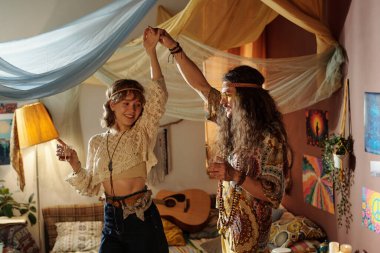 Mutlu çift bohem tarzında dans ediyor. Etrafı eklektik dekorlarla çevrili. Birbirlerine eşlik ediyorlar..