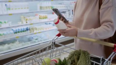Mandıra ürünleri listelerini kontrol eden ve süpermarkette alışveriş yaparken telefon kullanan tanınmayan yetişkin kadınların yakınlaşması, kopyalama alanı