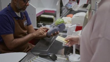 Erkek veznedarın, kredi kartıyla ödeme yapan kadına bankacılık terminali verişi.