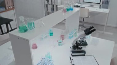 Modern uyuşturucu geliştirme laboratuvarında mikroskop yakınındaki masada renkli çözümler ve test tüpleri kullanan hiç kimse yok.