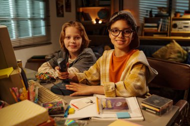 İki çocuk, rahat bir odada kitap ve oyun kartuşlarıyla çevrili eski bir video oyun konsoluyla oynuyorlardı. Kameraya bakmadan keyifli ve meşgul edici bir eğlence gösteriyorlardı.