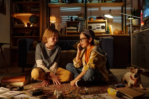 Çocuklar çeşitli oyunlar ve kitaplarla çevrili bir şekilde güzel aydınlatılmış oturma odası ortamında yerde otururken eğlenceli aktivitelere daldılar.