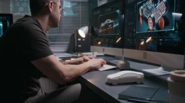 Kafkasyalı erkek otomotiv mühendisinin stüdyoda bilgisayar başında çalışırken, araç özelliklerini girerken klavyede yazarken, sonra kilden araba modelini alıp incelerken orta ölçekli bir fotoğraf.