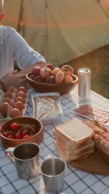 Ana kuzusu yumurta pişirirken dikey yakın çekim portatif soba üzerinde pastırmalı yumurta kamp alanında aile yemeği.