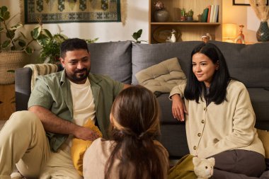 Aile portresi sıcak oturma odasında toplanıyor. Çevrede çeşitli dekor elementleriyle otururken ebeveynler bebekle ilgileniyorlar, sıcak ve davetkar bir ortam yaratıyorlar.