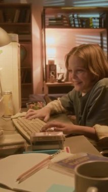 90ların nostaljik ortamında geçmişe dönük bilgisayar kullanan gülümseyen çocuğun dikey görüntüsü.