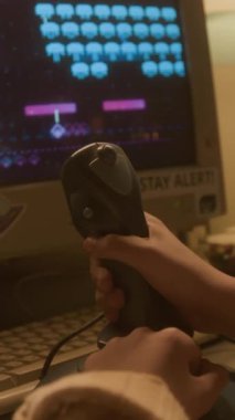 Retro video oyunu oynarken joystick kullanan tanınmayan çocuğun dikey yakın çekimi