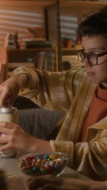 90 'lı yıllarda bilgisayar kullanan genç bir çocuğun video oyunu oynarken kola kutusu açtığı dikey çekim.