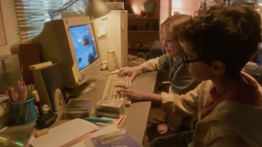 90 'ların nostaljik ortamında geçmişe dönük bilgisayar kullanan iki çocuğun yan görüntüsü. Arkadaşları öfkeyle kaybediyor ve bağırıyor.